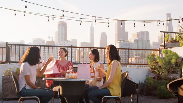 Freundinnen-Geburtstag-auf-Dachterrasse-mit-Skyline-der-Stadt-im-Hintergrund