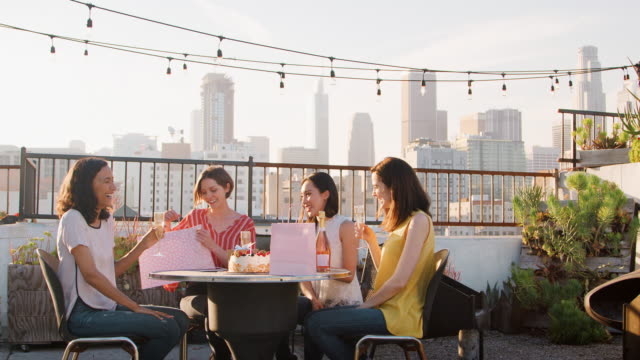 Freundinnen-Geburtstag-auf-Dachterrasse-mit-Skyline-der-Stadt-im-Hintergrund