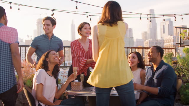 Freunde-versammelt-auf-Dachterrasse-zum-Geburtstag-mit-Skyline-der-Stadt-im-Hintergrund