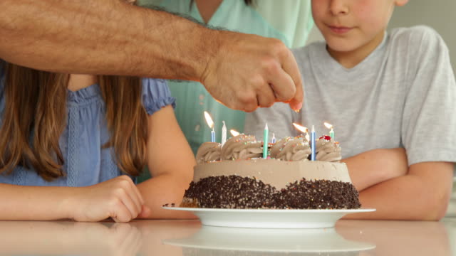 Vater-Beleuchtung-Kerzen-auf-Geburtstagskuchen-für-seine-Familie