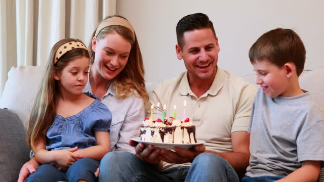 Happy-young-family-sitting-on-sofa-celebrating-a-birthday