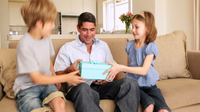 Niedliche-Kinder-gibt-Ihrem-Vater-präsentiert-auf-der-couch