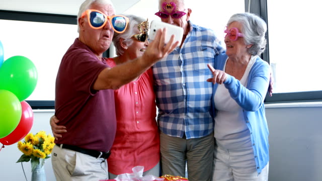 Senioren-nehmen-Selfie-auf-Handy-während-der-Geburtstagsfeier