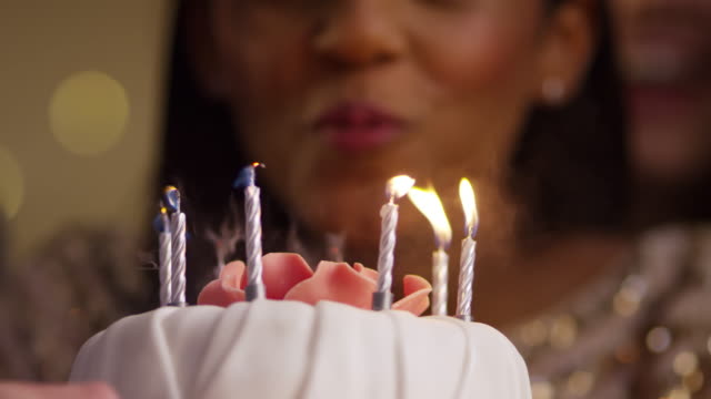 Frau-bläst-Kerzen-auf-Geburtstagskuchen