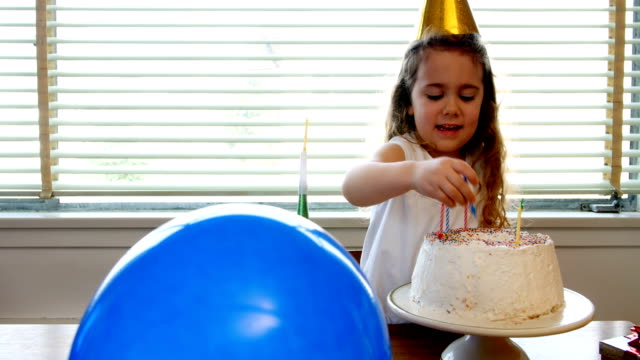 Girl-placing-candles-over-birthday-cake