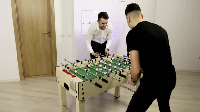 Happy-male-friends-hanging-out-together-and-playing-a-game-of-table-kicker-football.