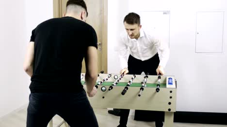 Two-young-men-play-table-soccer-in-the-office.