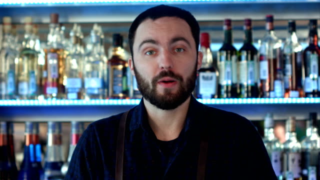 Positive-bartender-talking-to-a-camera-at-a-bar-counter