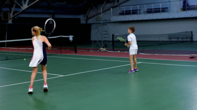 Sportliche-jungen-und-Mädchen-spielen-Tennis-auf-Platz-als-Team-zusammen