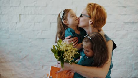 schöne-Töchter-geben-Mama-ein-Geschenk-und-Blumen