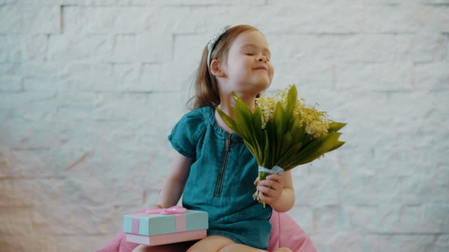 niedliche-kleine-Mädchen-zeigt-Blumen-und-ein-Geschenk