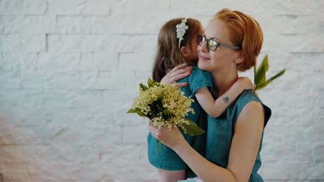 Mother-and-little-daughter-hug-each-other-with-flowers