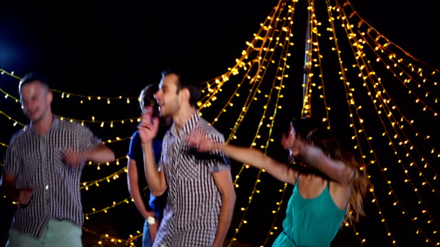 Young-and-energetic-friends-dance-and-sing-outside-at-the-disco-at-night