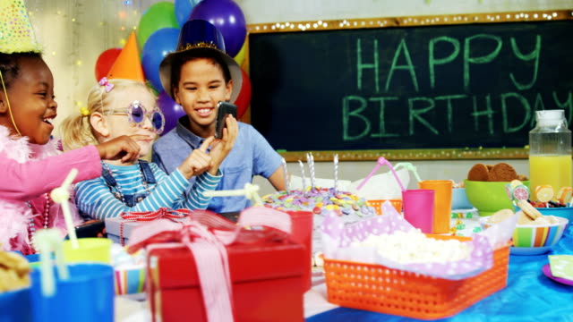 Kinder-betrachten-Bilder-im-Handy-während-Geburtstag-party-4k