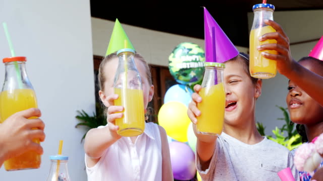 Kids-toasting-the-bottles-of-juice-in-the-backyard-of-house-4k