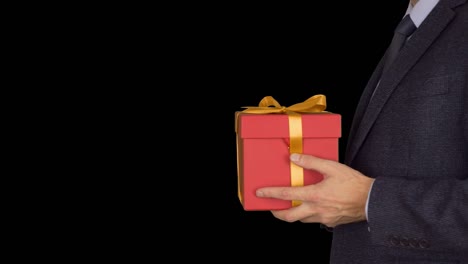 Caucasian-businessman-hold-and-give-red-gift-box.-Side-view.-Adult-man-in-classic-business-suit-hold-red-gift-box.-Alpha-channel-chroma-key-transparent-background.-Locked-down.