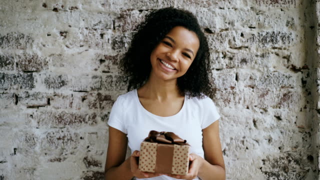 Porträt-des-jungen-glücklich-afrikanisches-Mädchen-Geschenkbox-halten-und-Lächeln-in-die-Kamera