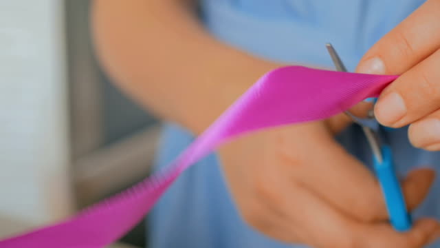Close-up-shot-of-woman-cutting-ribbon-of-wedding-bouquet-at-workshop