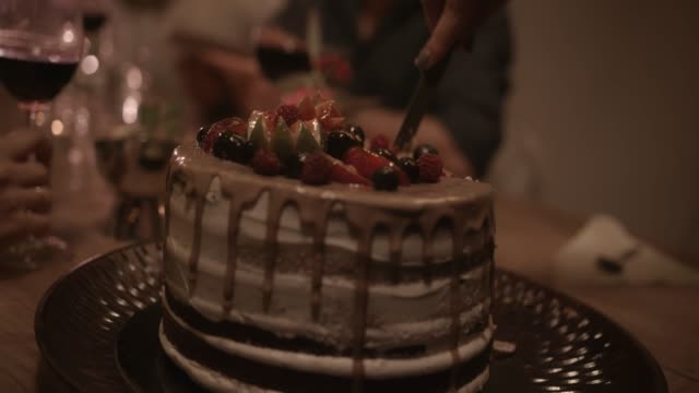 Nahaufnahme-von-Frau-schneiden-Scheiben-Gourmet-Dessert-Geburtstagstorte