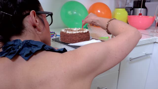 Mujer-de-decorar-torta-con-velas-sobre-la-mesa-en-la-cocina