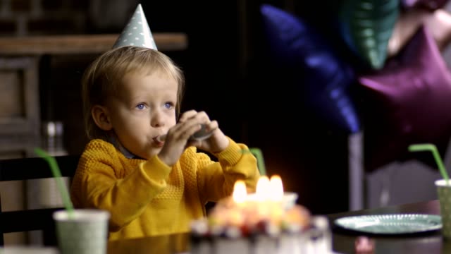 Sweet-toddler-blowing-birthday-horn-and-laughing