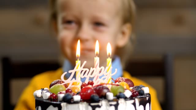 Primer-plano-del-muchacho-que-sopla-velas-en-el-pastel-de-cumpleaños