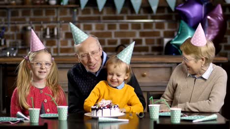 Boy-blowing-candles-on-cake-with-his-grandparents