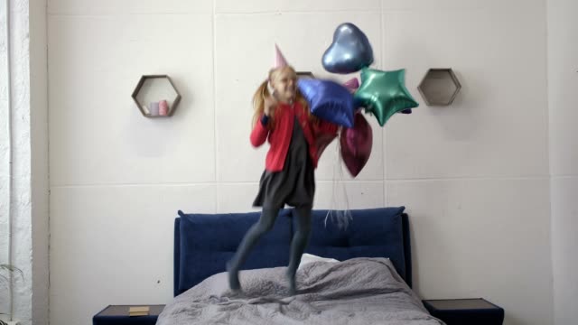 Teen-Mädchen-springen-auf-Bett-mit-Ballons-zum-Geburtstag