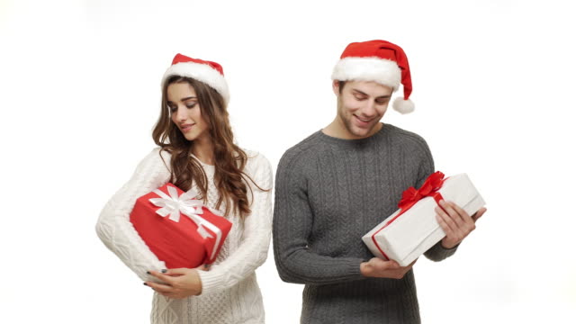 4k-young-couple-in-sweater-holding-present-and-treat-like-a-child-on-white-background.