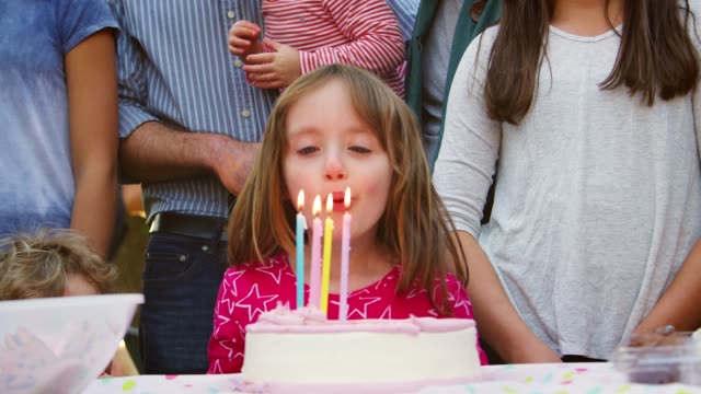 Junges-Mädchen-auf-ihrer-Gartenparty-Geburtstag-Kerzen-ausblasen