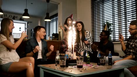 Pretty-girl-celebrates-birthday-with-her-friends.-Multi-ethnic-party-with-cake-and-Bengal-light-sparkling-firework.-4K
