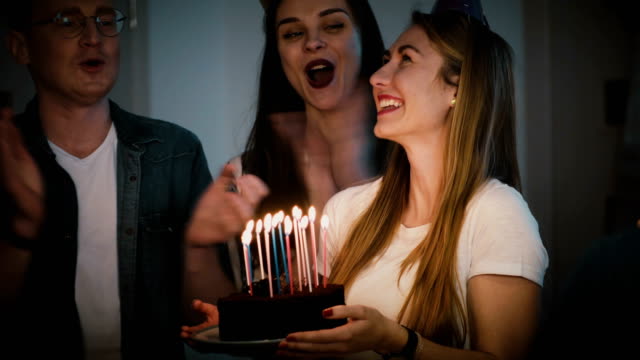 Beautiful-woman-makes-a-wish-and-blows-on-candles.-Diverse-multi-ethnic-group-celebrate-birthday-party-together.-4K