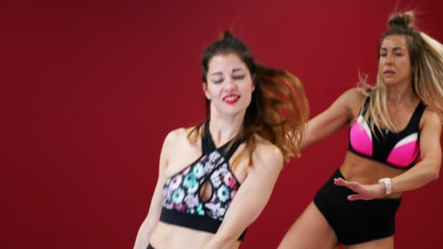 Schöne-sexy-Mädchen-auf-einem-roten-hintergrundwand-Fitness-Übungen-auf-einem-speziellen-Schuhen-Kango-Sprung
