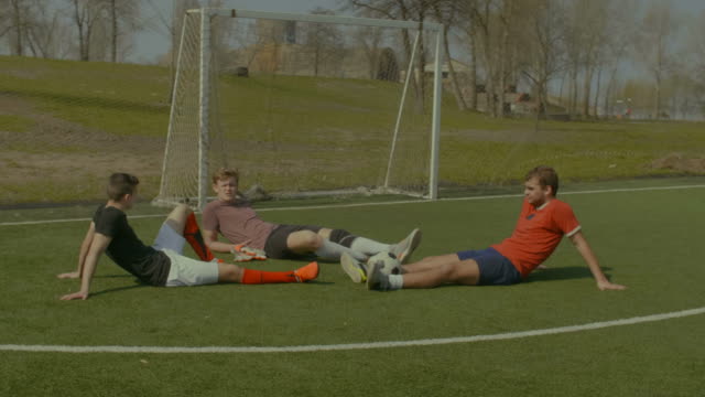 Footballers-relaxing-on-soccer-field-after-game