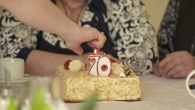 Senioren-bei-der-70.-Jahrestag-Feier.-Kuchen-mit-brennenden-Kerze-Nummer-70.