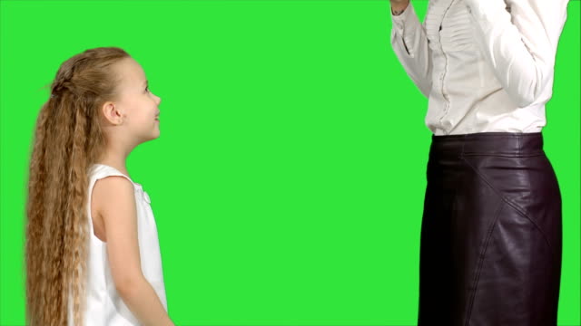 Little-girl-giving-a-gift-to-her-mother-and-kissing-on-a-Green-Screen,-Chroma-Key