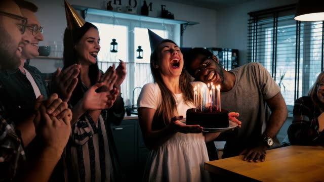 Glückliches-Mädchen-Europäischen-Holding-Kuchen,-dass-ein-Wunsch-und-weht,-multiethnischen-Freunde-singen-Spaß-Geburtstagsparty-Zeitlupe