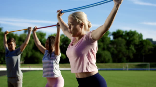 Mujer-con-niños-haciendo-ejercicio-en-el-campo-de-deportes