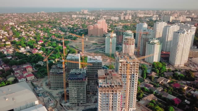 Aerial-drone-shot.-Construction-of-high-rise-buildings-in-the-developing-area-of-a-large-city.-Sunset-shot.-Span-above-the-construction-site.-go-from-wide-shot,-pull-back-to-a-close-up