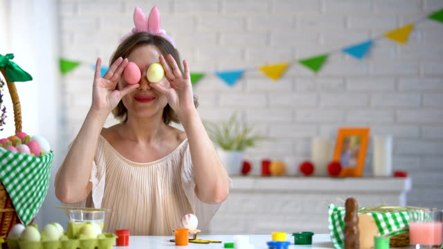 Mujer-alegre-poniendo-huevos-de-Pascua-a-ojos-divirtiéndose-y-disfrutando-de-la-fiesta-brillante