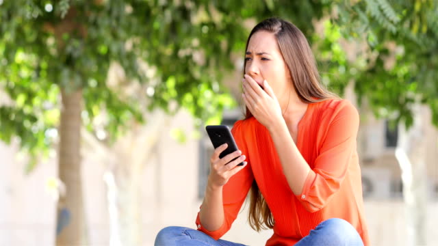 Woman-yawning-using-a-smart-phone
