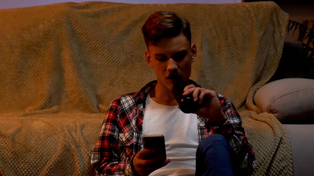 Boy-drinking-beer-at-home,-chatting-with-friends-in-social-network,-awkward-age