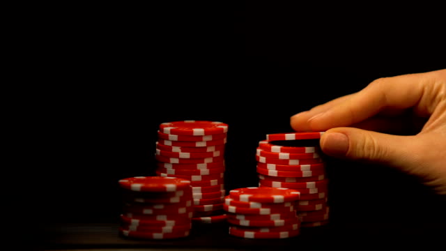 Mano-poniendo-fichas-de-Poker-aisladas-en-negro,-la-tentación-de-todo-en-la-apuesta,-la-adicción