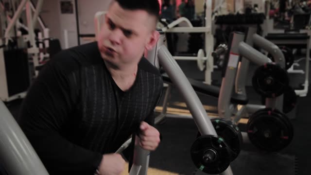 Cheerful-fat-man-performs-the-wrong-exercise-in-the-gym