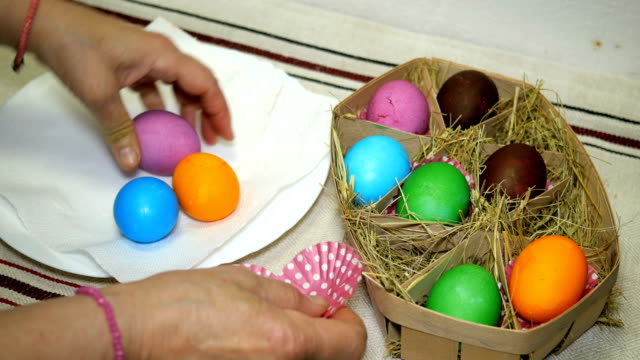 Woman-puts-colorful-Easter-eggs-in-basket-with-hay.