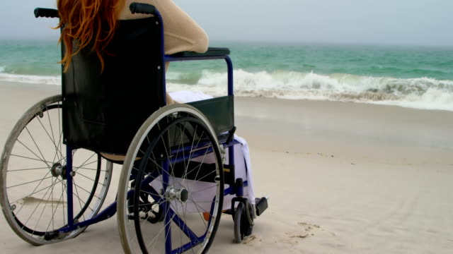 Blick-auf-Frau,-die-auf-dem-Rollstuhl-am-Strand-4k-sitzt
