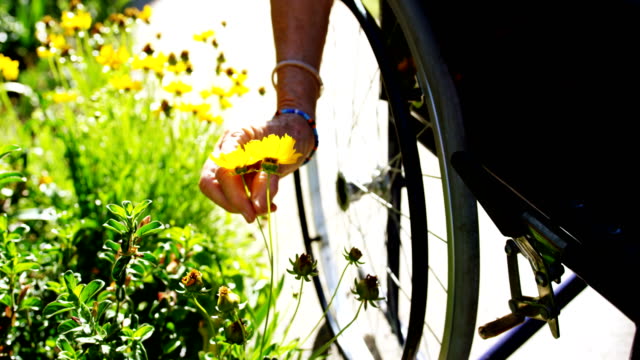 Close-up-of-disabled-Senior-woman-holding-a-flower-in-the-garden-of-nursing-home-4k