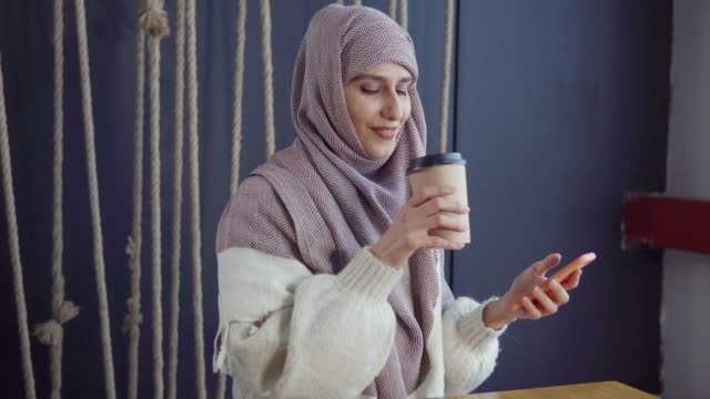 Muslimische-Mädchen-in-einem-Café-mit-Smartphone