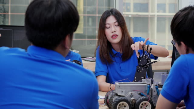 Female-engineer-having-conversation-to-robot-project-with-her-team-at-lab.-Technology-and-innovation-concept.