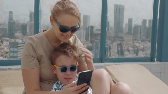 Mutter-und-Kind-mit-Handy-beim-Entspannen-auf-dem-Dach-des-Hotels-in-Tel-Aviv,-Israel